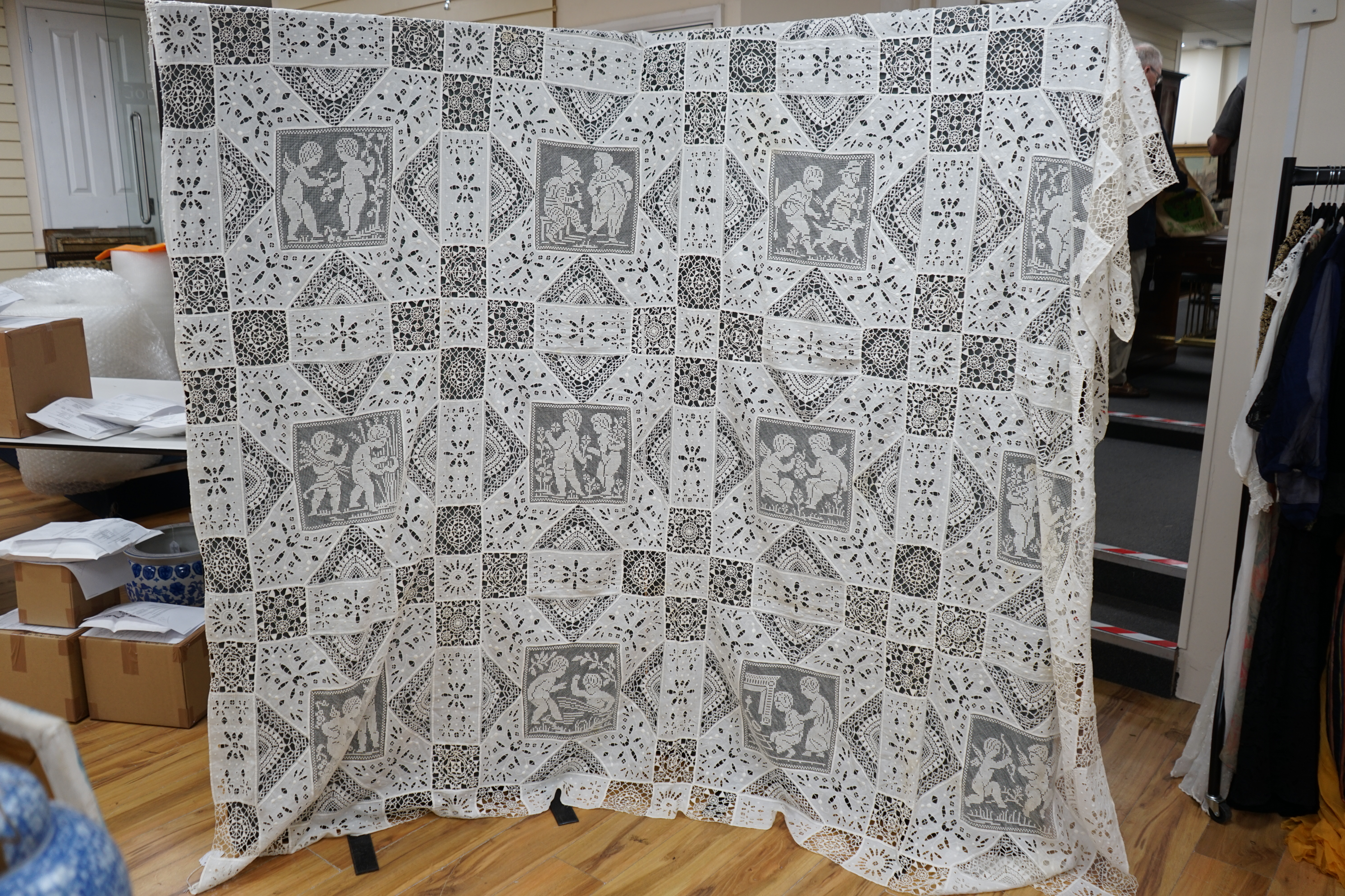 An early 20th century Italian ornate bedcover, worked with square fillet lace insertions of putti, white multi patterned cut work squares on fine linen and similar multi patterned needle lace squares, creating a unique b